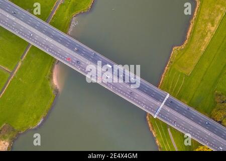 Vue aérienne de dessus en bas de l'immense rivière des basses terres IJssel avec pont de l'autoroute à travers le paysage agricole. Zwolle, province d'Overijssel, pays-Bas. Dr Banque D'Images