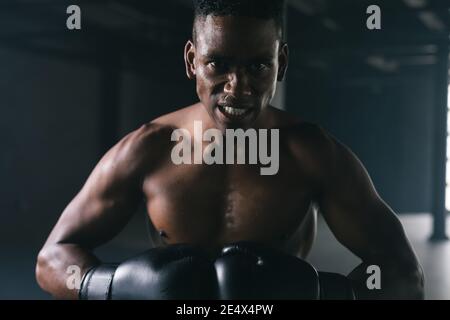 Portrait d'un homme afro-américain portant et pointant des gants de boxe dans un bâtiment urbain vide Banque D'Images