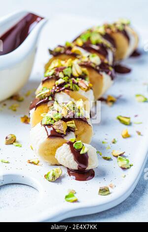 Sushi sucré à la banane avec chocolat et noix, fond blanc. Concept de dessert végétalien. Banque D'Images