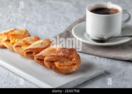 Petits gâteaux faits maison avec fromage cottage et une tasse de café sur fond gris. Cuisson maison Banque D'Images