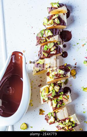 Sushi sucré à la banane avec chocolat et noix, fond blanc. Concept de dessert végétalien. Banque D'Images