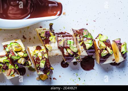 Sushi sucré à la banane avec chocolat et noix, fond blanc. Concept de dessert végétalien. Banque D'Images