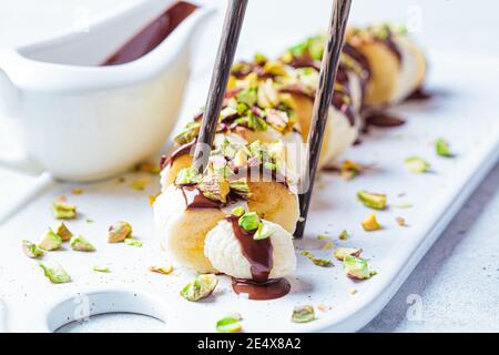Sushi sucré à la banane avec chocolat et noix, fond blanc. Concept de dessert végétalien. Banque D'Images