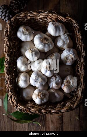 Bulbes à l'ail dans un panier sur fond de bois. Vue de dessus. Banque D'Images
