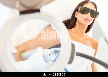 Jeune femme avec des lunettes de protection pour l'épilation au laser bras sous la loupe Banque D'Images