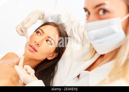 Jeune femme en tant que patient avec dermatologue lors de la consultation sur la peau serrage sur la face Banque D'Images