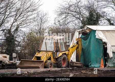 Vieux creuseur jaune rouillé roues rouges bras télescopique abandonné cassé Pelle en bas, benne télescopique JCB, ferraille laissée derrière sur site Banque D'Images