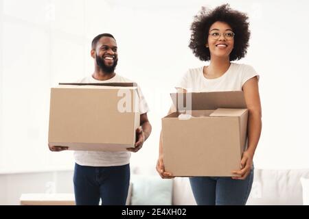 Les conjoints Afro-américains transportant des boîtes dans une nouvelle maison Banque D'Images