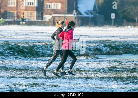 WIMBLEDON LONDRES, ROYAUME-UNI 25 JANVIER 2021. Deux joggeurs féminins qui courent sur le paysage enneigé après une forte chute de neige ont frappé Londres dimanche avec des températures qui chutent à -5 °C la nuit dernière. Le bureau du met a émis un avertissement jaune pour la glace dans le sud-est de l'Angleterre avec des prévisions de températures inférieures à zéro. Credit: amer ghazzal / Alamy Live News Banque D'Images