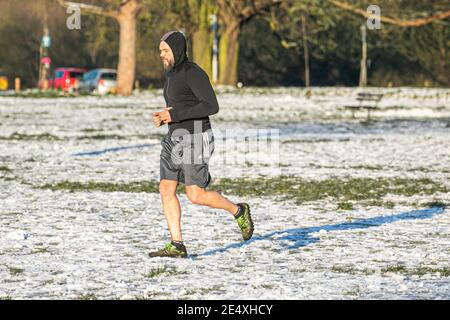 WIMBLEDON LONDRES, ROYAUME-UNI 25 JANVIER 2021. Un homme qui s'est jogging sur le paysage enneigé lors d'une matinée froide et nette sur Wimbledon Common dans le sud-ouest de Londres après une forte chute de neige a frappé Londres dimanche avec des températures qui ont plongé à -5 °C la nuit dernière. Le bureau du met a émis un avertissement jaune pour la glace dans le sud-est de l'Angleterre avec des prévisions de températures inférieures à zéro. Credit: amer ghazzal / Alamy Live News Banque D'Images