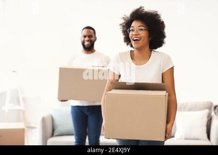 Un couple africain excité transportant des boîtes mobiles entre dans sa propre maison Banque D'Images