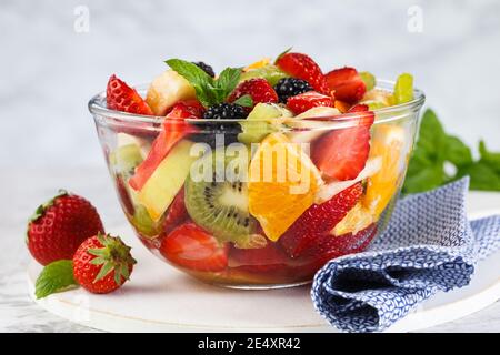 Salade de fruits frais saine dans un bol sur fond gris. Banque D'Images