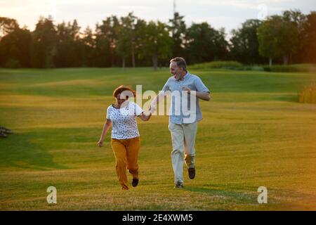 Un couple heureux et riant qui court sur l'herbe. Banque D'Images