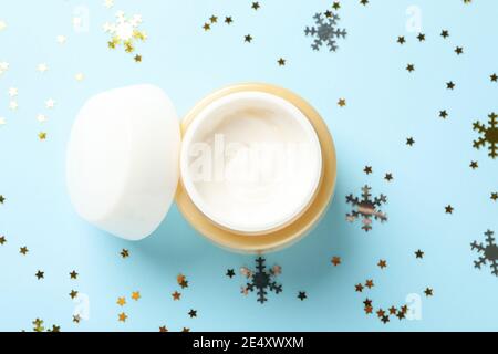 Crème cosmétique sur un fond bleu avec des paillettes, un moment de soins festifs étincelant Banque D'Images