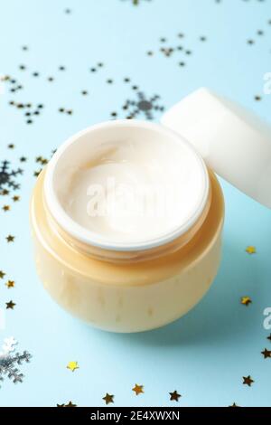 Crème cosmétique sur bleu avec paillettes, un moment de crème de soins festif et étincelant Banque D'Images