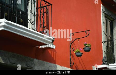 Façade traditionnelle de maison coloniale avec un mur de stuc vénitien et des pots de fleurs en argile suspendus à Atlixco, Puebla Mexique. Banque D'Images