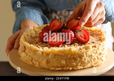 Femme met des fraises sur un délicieux gâteau Napoléon Banque D'Images