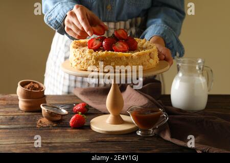 Femme met des fraises sur un délicieux gâteau Napoléon Banque D'Images