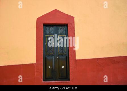 Ancienne façade de maison coloniale avec un mur en stuc vénitien et une porte d'entrée en fer fait à la main à Atlixco, Puebla Mexico. Banque D'Images