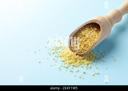 Scoop avec du couscous cru sur un fond bleu en gros plan, un grain de blé facile à cuire pour des plats sains Banque D'Images