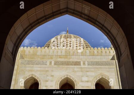 MUSCAT, OMAN - 8 FÉVRIER 2018 : un dôme blanc contrastant avec le ciel bleu de la Grande Mosquée du Sultan Qaboos. La scène est vue de derrière une arche. Banque D'Images