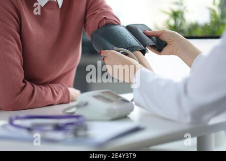 Le médecin mesure la tension artérielle du patient à son rendez-vous Banque D'Images