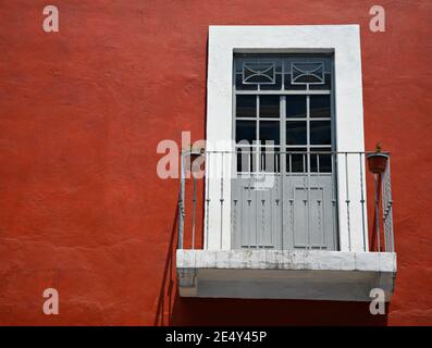 Façade de maison coloniale avec un mur de stuc vénitien, une fenêtre avec garniture blanche et main de balcon en fer forgé à Atlixco, Puebla Mexique. Banque D'Images