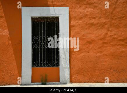 Façade de maison coloniale avec un mur en stuc vénitien et une fenêtre avec des grilles en fer artisanales à Atlixco, Puebla Mexique. Banque D'Images