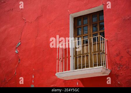 Ancienne façade de maison coloniale avec un mur de stuc et une fenêtre en bois avec balustrade de balcon en fer fait à la main à Atlixco, Puebla Mexique. Banque D'Images