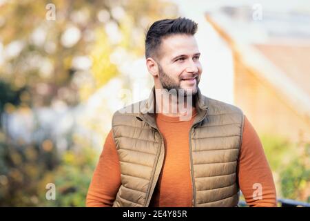 Photo portrait d'un beau homme debout à l'extérieur et joyeux temps d'automne. Banque D'Images