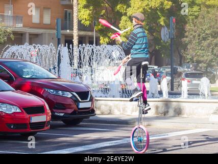 VALENCE, ESPAGNE - 15 janvier 2021 : un clown marionnettiste profite du feu rouge pour offrir un spectacle de jonglage aux conducteurs sur la voie publique pour gagner un vin Banque D'Images