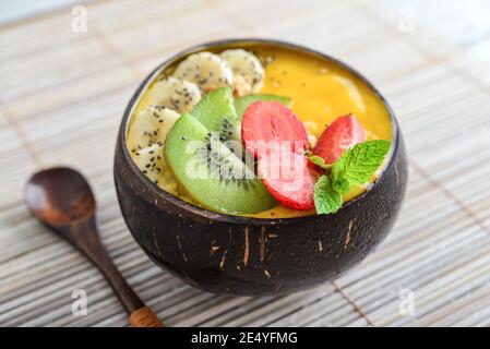 Bol à smoothie à la mangue avec graines de banane, fraise, kiwi, granola et chia dans un bol de noix de coco Banque D'Images