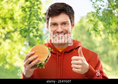 Heureux jeune homme avec hamburger showing Thumbs up Banque D'Images