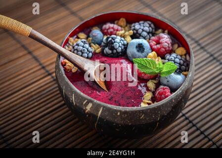 Bol à smoothie Açai aux graines de myrtille, de mûre, de framboise, de granola et de chia dans un bol en noix de coco Banque D'Images