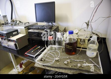 Poste de travail dans un vrai laboratoire scientifique, assez désordonné. Y compris un ordinateur, un bloc-notes, un stylo, des bocaux d'échantillons, des clés et divers équipements sur un établi. Banque D'Images