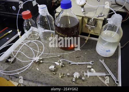 Poste de travail dans un vrai laboratoire scientifique, assez désordonné. Y compris des récipients à échantillons, des clés et divers équipements sur une paillasse. Mise au point sélective. Banque D'Images