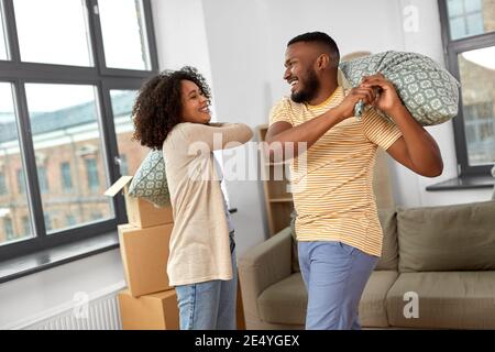 couple heureux ayant un combat d'oreiller dans la nouvelle maison Banque D'Images