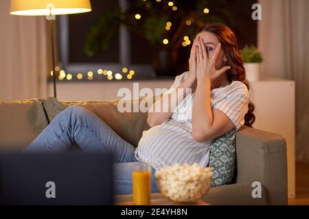 femme enceinte effrayée regardant la télévision à la maison Banque D'Images