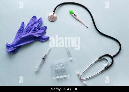 Vaccin et seringue avec stéthoscope et gants médicaux sur fond bleu. Vaccination. COVID-19, SRAS - concept de vaccin CoV2. Vue de dessus. Copier l'espace Banque D'Images