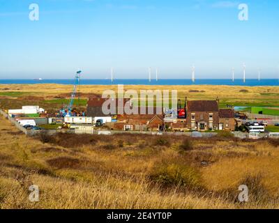 Catégorie 2 classée ferme de Marsh, autrefois isolée sur le marais de Warrenby, maintenant entourée par l'industrie et avec Redcar Wind Farm et les liens de golf derrière Banque D'Images