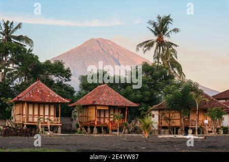 Bungalows traditionnels en bois balinais sur la plage avec vue sur le volcan Agung au lever du soleil, à Amed, Bali Banque D'Images