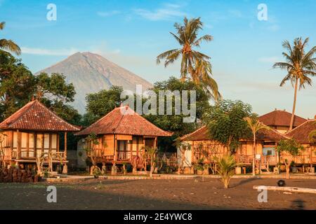 Bungalows traditionnels en bois balinais sur la plage avec vue sur le volcan Agung au lever du soleil, à Amed, Bali Banque D'Images