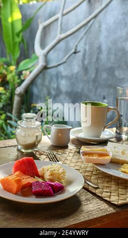 Petit déjeuner touristique traditionnel à Bali : pain grillé, œufs brouillés, café et fruits frais Banque D'Images