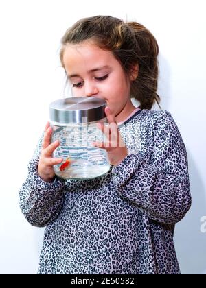 Petite fille tenant un pot avec un poisson orange à l'intérieur. Arrière-plan blanc. Banque D'Images