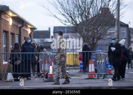 Cardiff, pays de Galles, Royaume-Uni.25 janvier 2020.Un homme en uniforme militaire mène un couple âgé au début d'une file d'attente pour le vaccin contre le coronavirus à l'extérieur d'un centre de vaccination dans la région de Splott à Cardiff.Le ministre de la Santé du pays de Galles, Vaughan Gething, a déclaré aujourd'hui qu'il n'était pas clair si l'engagement de vacciner 70 % des personnes âgées de plus de 80 ans et celles vivant dans des foyers de soins avait été atteint.Crédit : Mark Hawkins/Alay Live News Banque D'Images