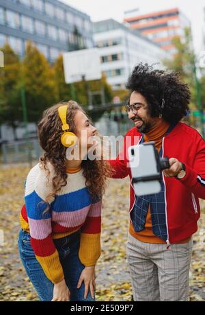 Un jeune couple avec un smartphone fait de la vidéo pour les médias sociaux en plein air dans le parc. Banque D'Images