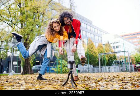 Un jeune couple avec un smartphone fait de la vidéo pour les médias sociaux en plein air dans le parc. Banque D'Images