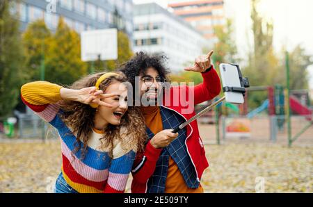 Un jeune couple avec un smartphone fait de la vidéo pour les médias sociaux en plein air dans le parc. Banque D'Images