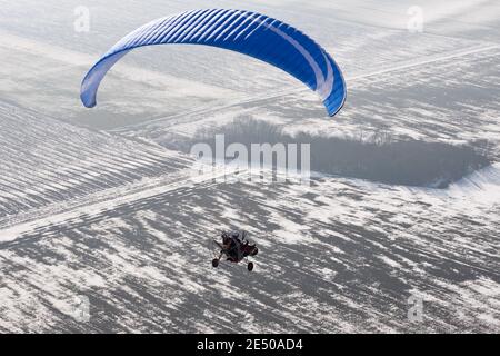 Parapente buggy motorisée ou paramoteur vue du ciel à La France survolant des champs enneigés en hiver Banque D'Images