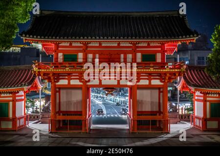 Prise de vue symétrique d'un temple japonais rouge, avec une lumière de rue et de ville en arrière-plan Banque D'Images